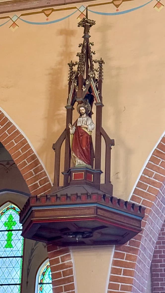 Figura Chrystusa z otwartą księgą na baldachimie ambony
